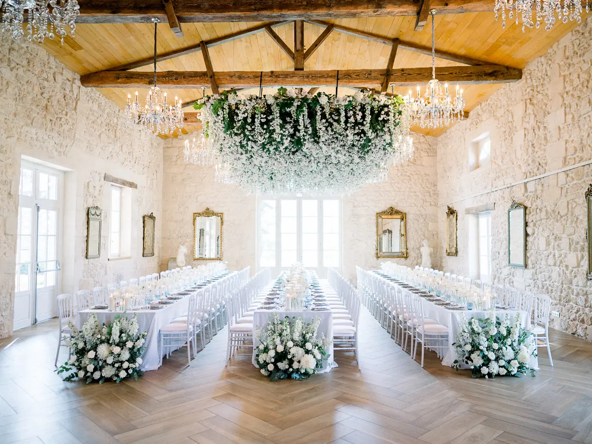 Château reception hall with a floral chandelier and long tables set for dinner