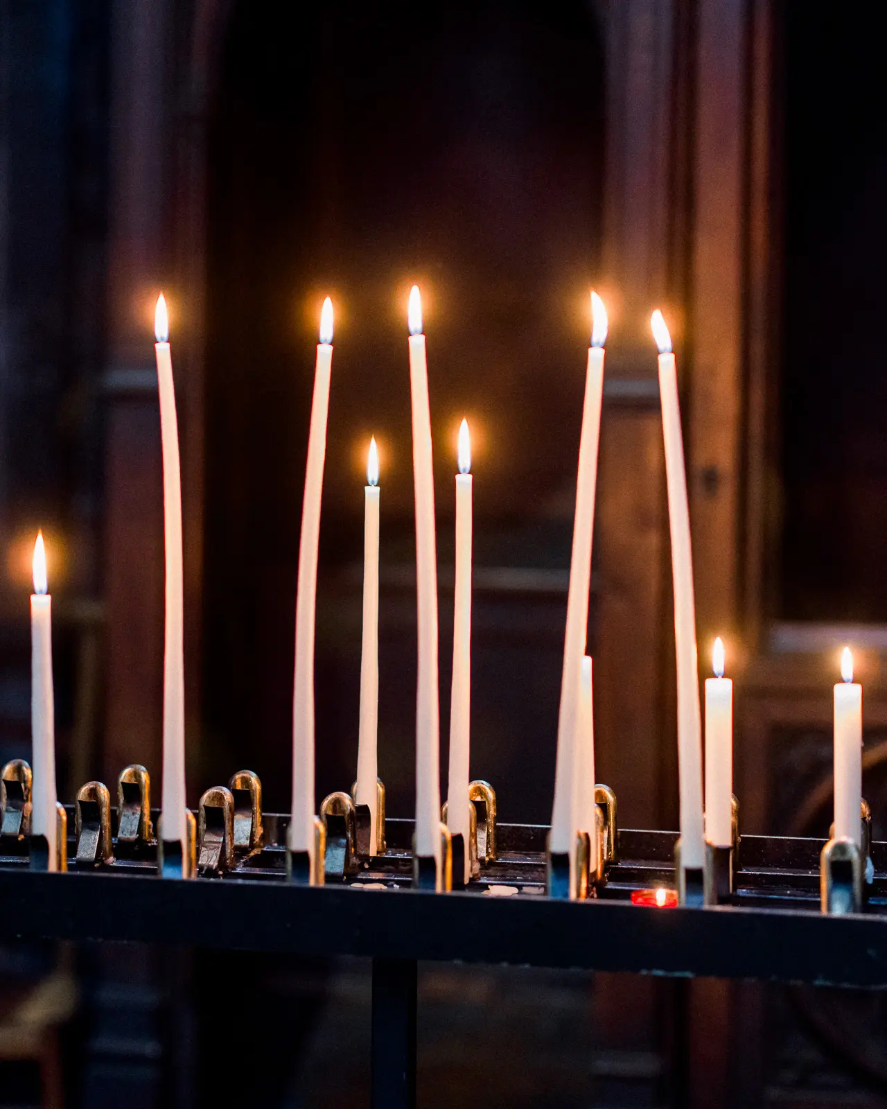 Lit candles in a church, from a christening photo story in Bordeaux