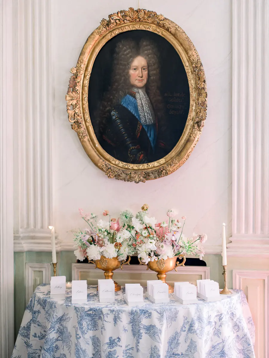 Plan de table fleuri sur nappe toile de Jouy, sous un portrait ancien au cadre doré