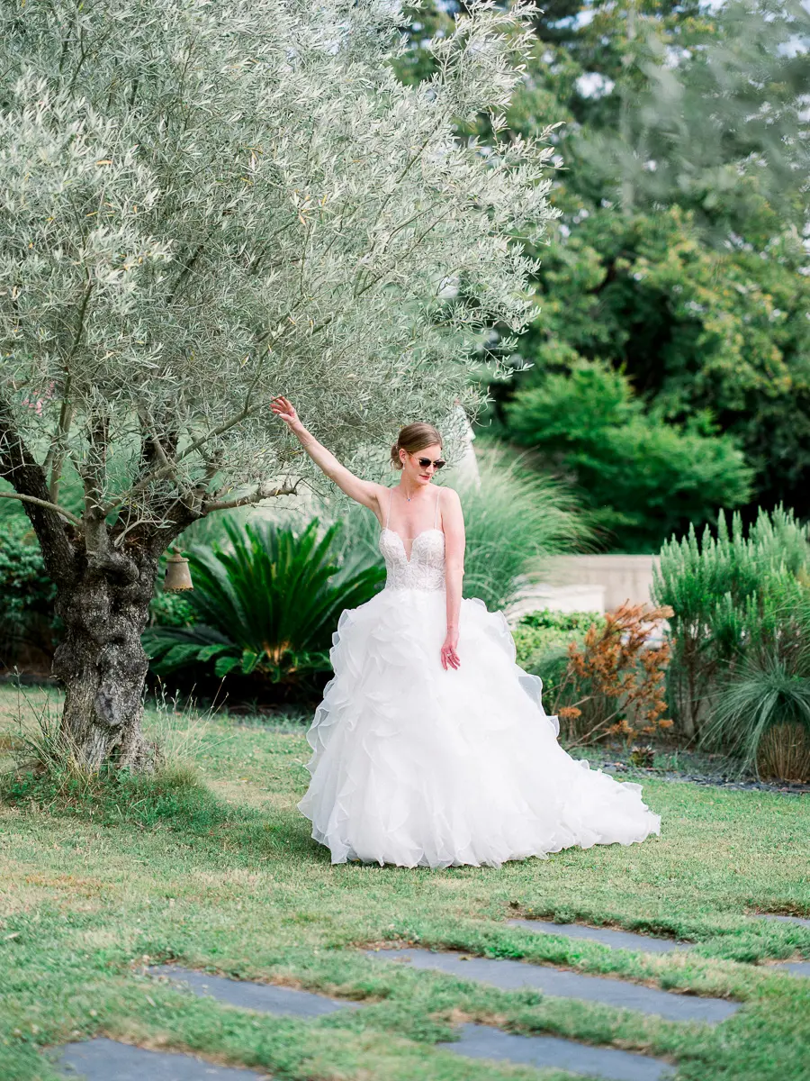 Mariée en robe à volants saluant de la main dans le jardin du Château Gassies