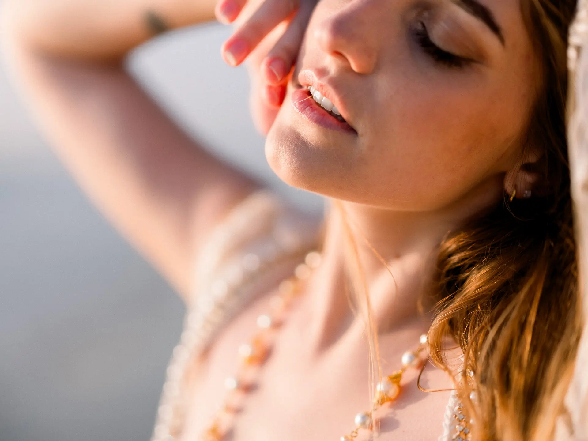 Bride with eyes closed and a pearl necklace in warm golden light
