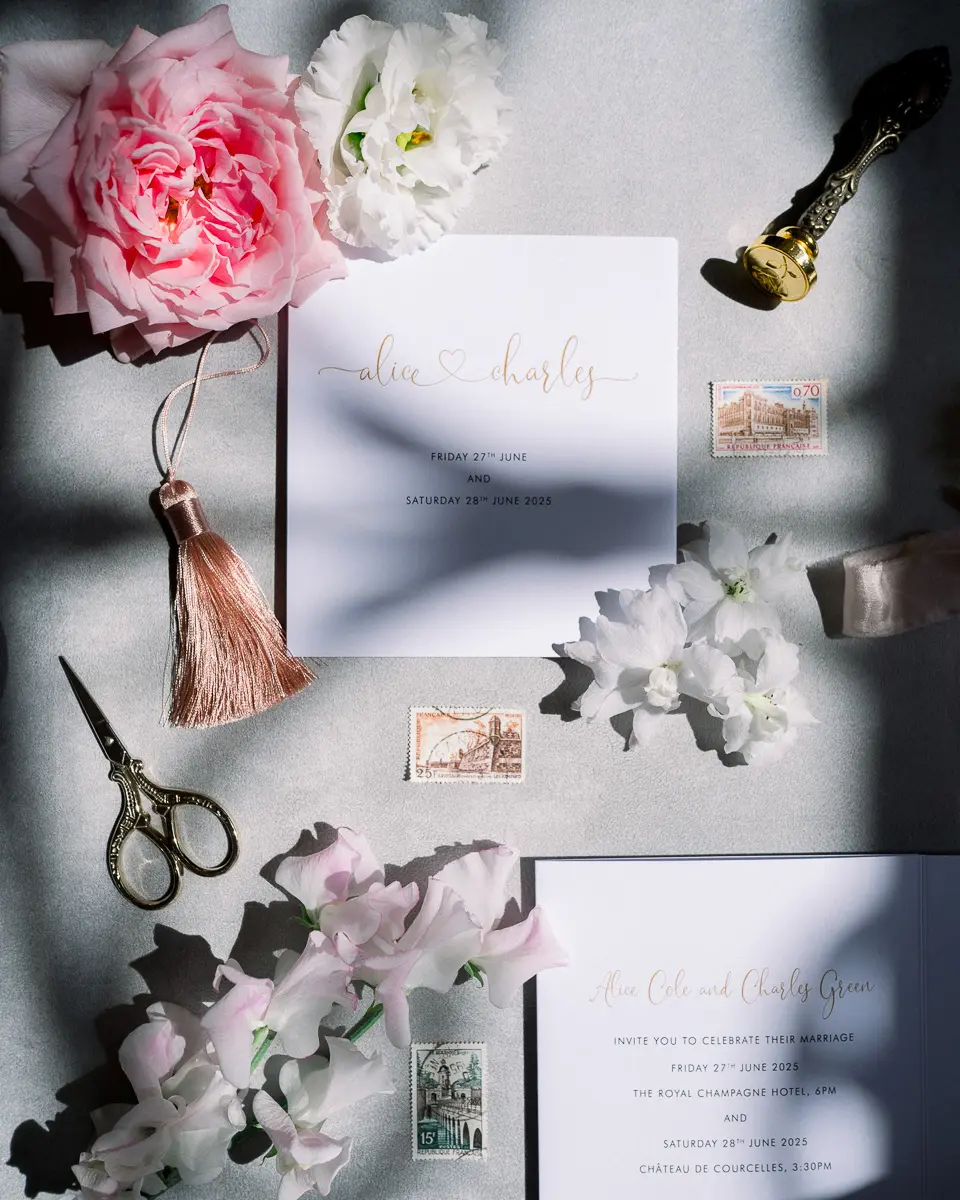 Papeterie de mariage, fleurs roses, ciseaux dorés et cachet de cire posés à plat